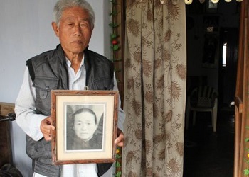 Wang Qi memegang foto ibundanya.(BBC)